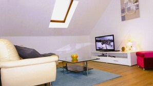 A living room with a sofa, a coffee table, a TV, and a lamp.