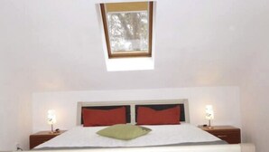 A bedroom with a bed, two bedside tables, and a window.