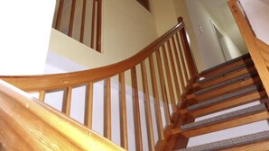 A wooden staircase with a handrail and a textured floor.