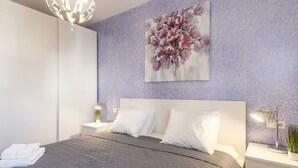 A modern bedroom with a large bed, white headboard, and a floral painting on the wall. - "Villa Tango1" mit eigenem Pool by Interhome (Trogir/Okrug Donji)