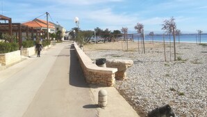 Une promenade en bord de mer, avec un muret en pierre, une plage et une vue dégagée sur la mer.