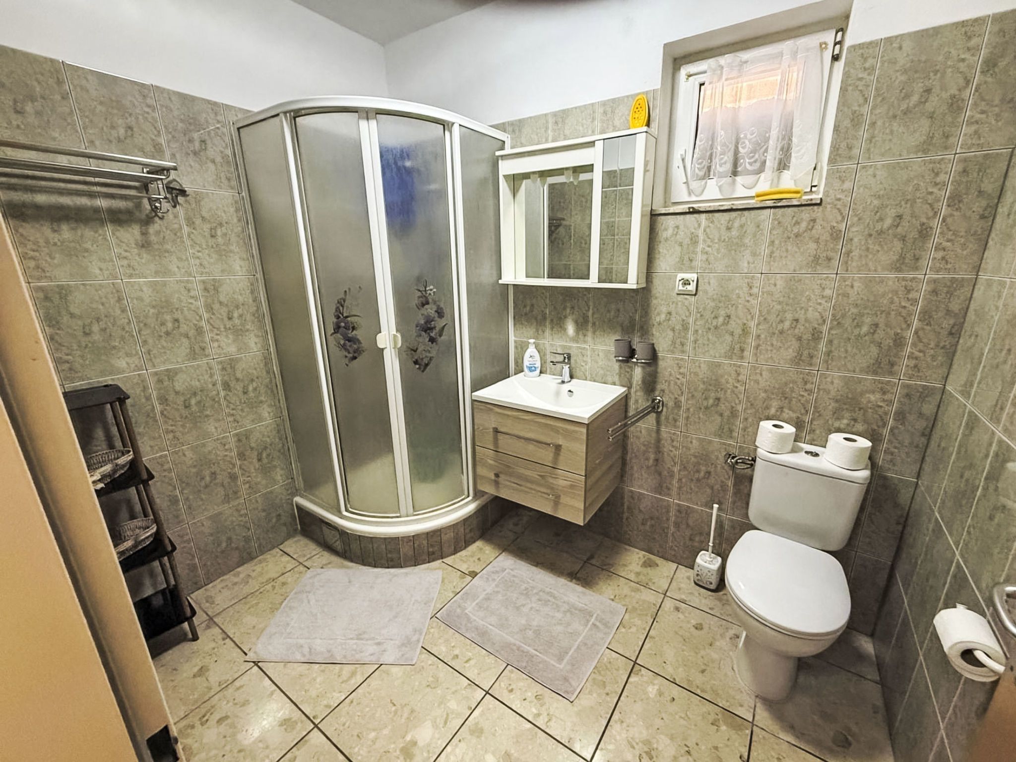 A bathroom with a shower, toilet, sink, and a mirror.