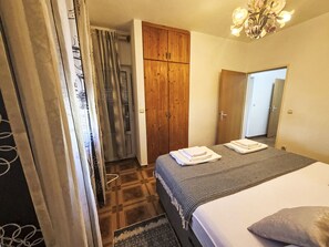 A bedroom with a bed, a wardrobe, a mirror, and a chandelier. - Wohnung Antica bei Queen beach Nin by Interhome (Nin)