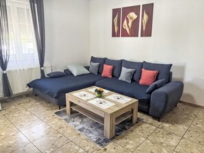 Ein modernes Wohnzimmer mit einem dunkelblauen Sofa, einem Holztisch und einem gemusterten Teppich.