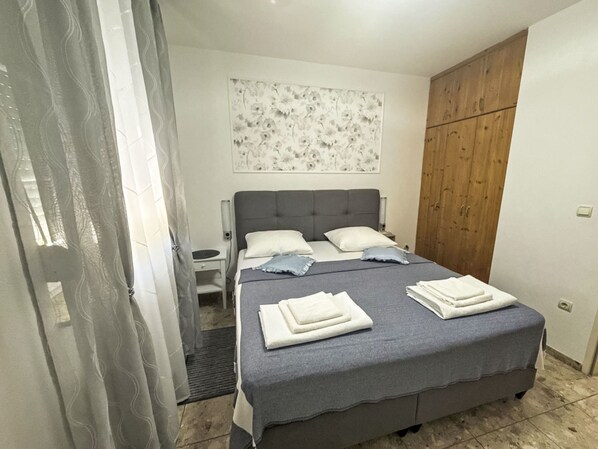 Une chambre à coucher comprenant un lit, une table de chevet, une armoire en bois et une décoration murale à motifs floraux.