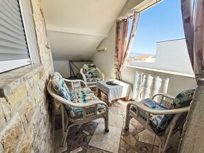 A balcony with wicker furniture, a small table, and a view of the city. - Wohnung "Antica 05" direkt am Strand by Interhome (Nin)