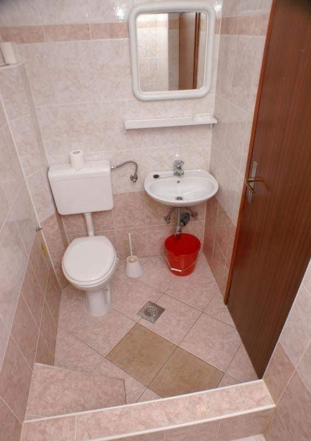Un baño pequeño con inodoro, lavamanos y espejo sobre el lavamanos.