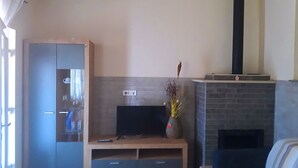 Ein Wohnzimmer mit Fernseher, Kamin und Kleiderschrank.