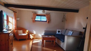 A cozy living room with a sofa, a small table, and a wicker chair. - Reetdachhaus Petra by Interhome (Helse)