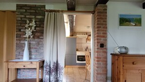 A kitchen with a brick wall, a wooden cabinet, and a white radio on top. - Reetdachhaus Petra by Interhome (Helse)