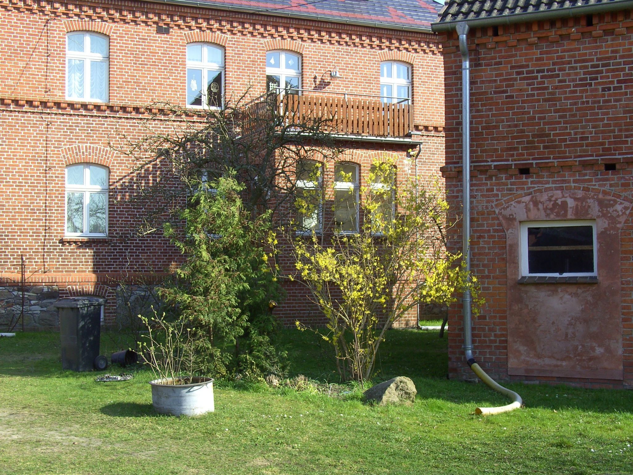 Ein Backsteinhaus mit Balkon, Blumentopf und Steinmauer.