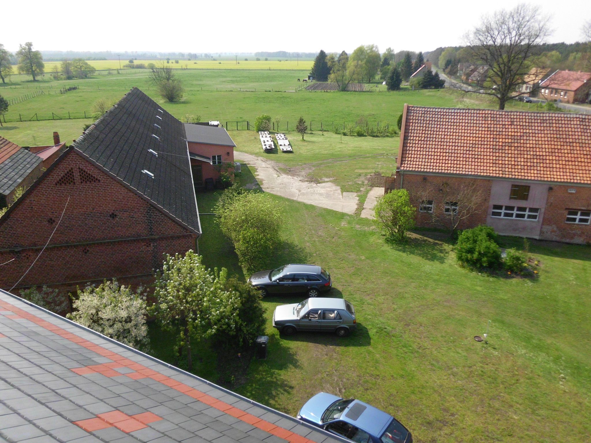 Un quartier résidentiel avec des maisons, un champ d’herbe et des voitures garées.