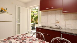 Eine kleine Küche mit Essbereich, ausgestattet mit Backofen, Spüle und Esstisch mit Stühlen.