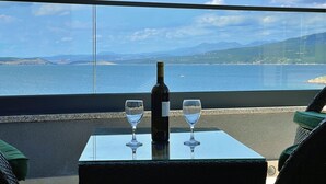 Un balcon avec une table, deux verres à vin et une bouteille de vin.