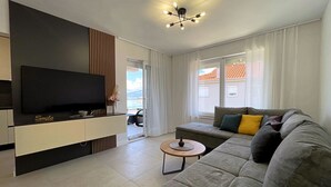 Un salon moderne doté d’un téléviseur à écran plat, d’un canapé, d’une table basse et d’un balcon offrant une vue agréable.