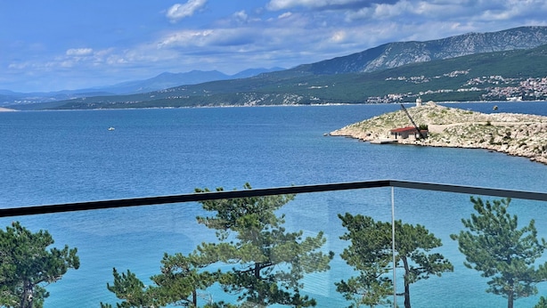 Une vue sur la côte, avec un ciel dégagé, une étendue d’eau et une chaîne de montagnes à l’horizon.