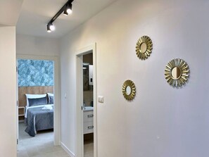 Une chambre d’hôtel moderne équipée d’un lit, d’un dressing et de trois miroirs fixés au mur.