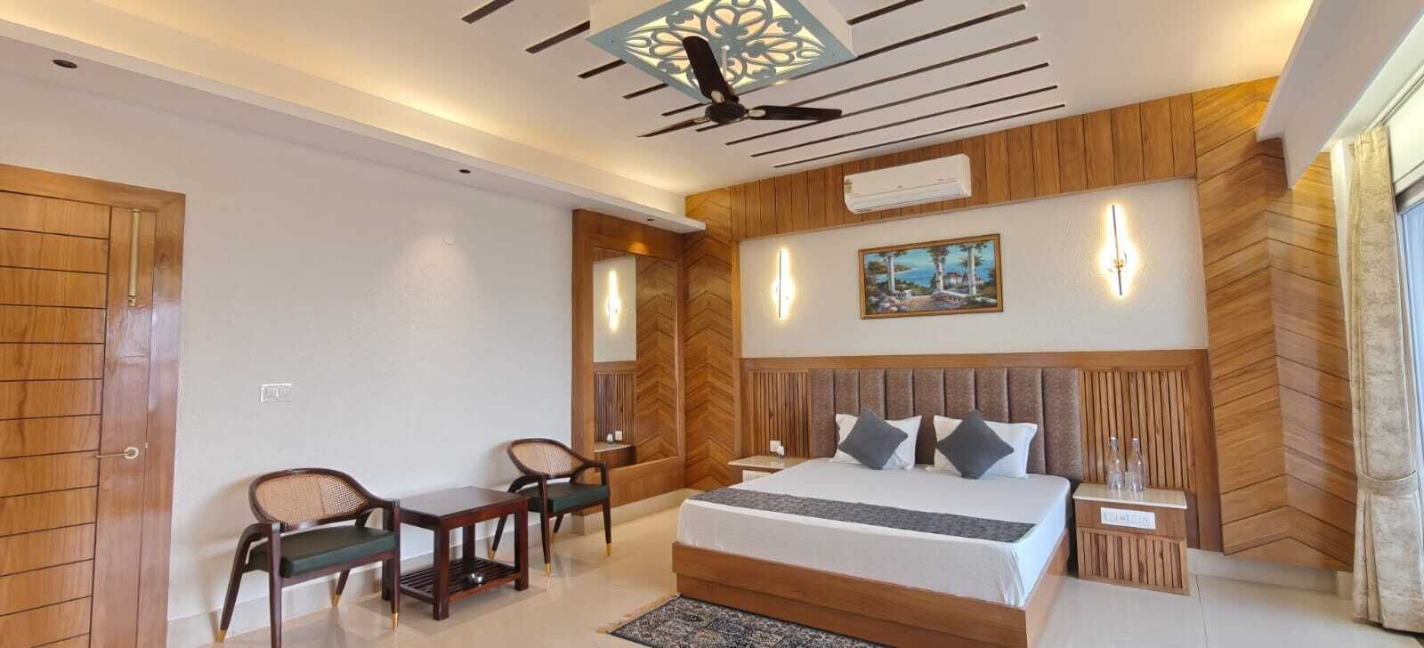 A bedroom with a bed, two chairs, a nightstand, and a wall-mounted air conditioner.