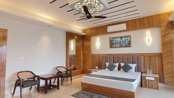 A bedroom with a bed, two chairs, a nightstand, and a wall-mounted air conditioner.
