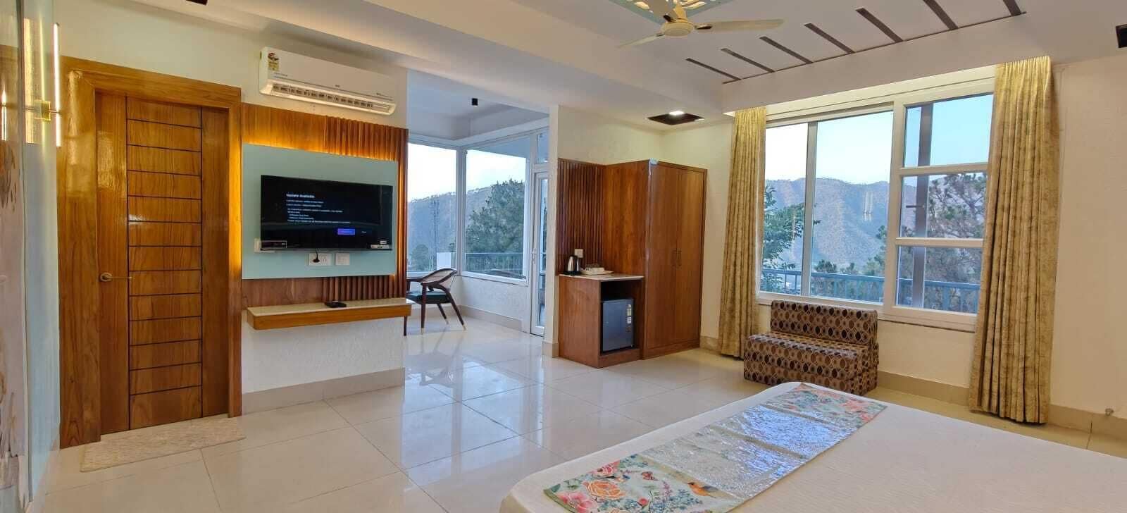 Habitación de hotel con un ventanal grande, televisor de pantalla plana, sofá y zona de escritorio.
