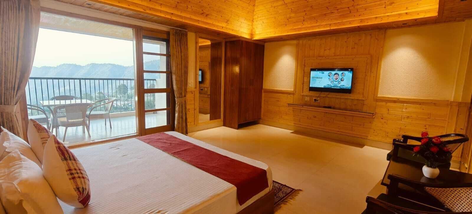 Een hotelkamer met een bed, een televisie, een balkon en een houten inrichting.