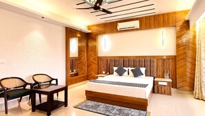 A modern bedroom with a bed, bedside tables, a desk, and chairs. - The Royal Terrace (Kasauli)
