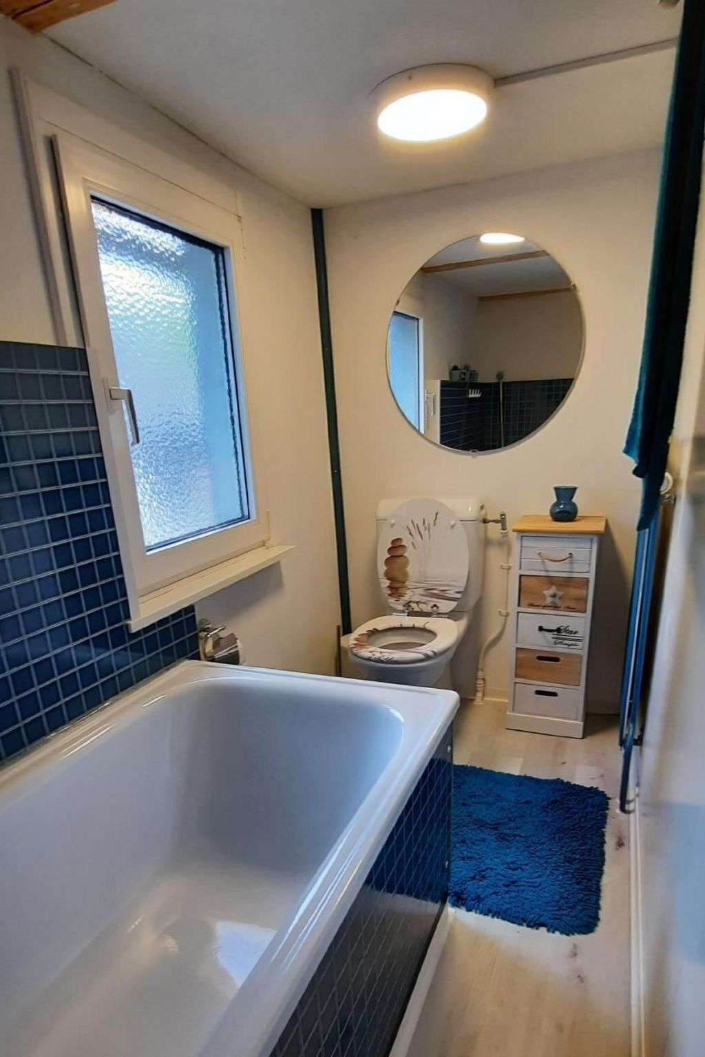 A bathroom with a bathtub, toilet, and a mirror.