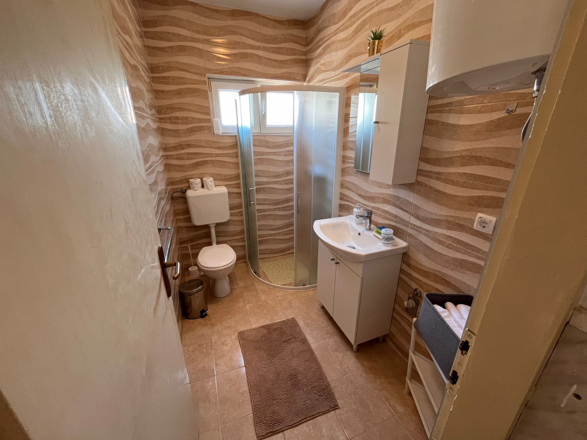 Ein Badezimmer mit Toilette, Dusche, Waschbecken und einem Spiegel über dem Waschbecken.