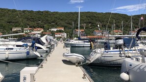 Ein Yachthafen mit mehreren anglegerten Booten, bewölkter Himmel und ein Hügel mit Gebäuden im Hintergrund.