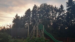 A playground with a slide and climbing structures, surrounded by trees and greenery. - auf dem Bauernhof by Interhome (Lütisburg Station)