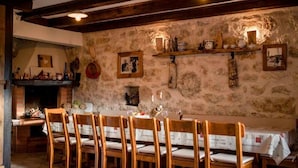 A rustic dining area with a long wooden table, chairs, and a stone wall. - Tolles Ferienhaus in Supetarska Draga mit Garten by Interhome (Rab/Supetarska Draga)