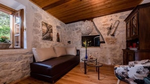 A cozy room with a stone wall, wooden ceiling, a sofa, a small table, and a cabinet. - Tolles Ferienhaus in Supetarska Draga mit Garten by Interhome (Rab/Supetarska Draga)
