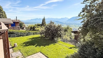 A residential property with a well-maintained lawn, a wooden deck, and a view of distant mountains.