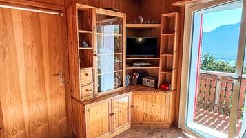 A wooden interior with a television, cabinets, and a sliding glass door to a balcony.