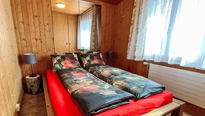 Een houten kamer met een bed, twee nachtkastjes en een raam met gordijnen.