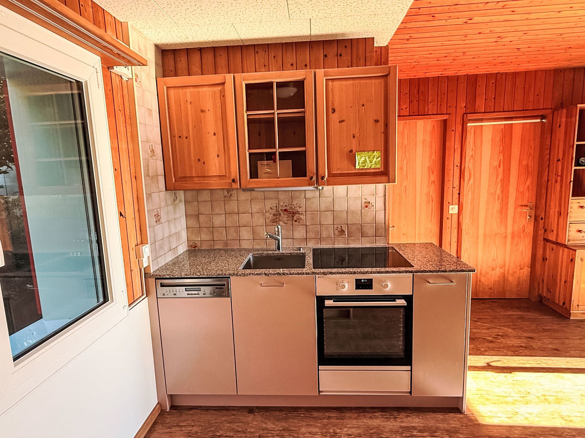A kitchen with wooden cabinets, a dishwasher, an oven, and a window.