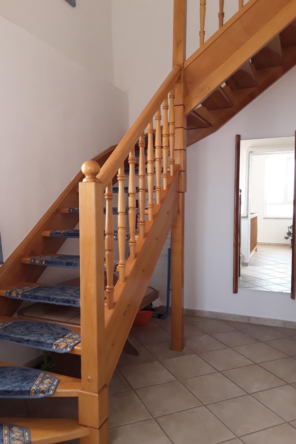 A wooden staircase with blue patterned steps leading to a landing.