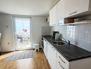 A compact kitchen with a black countertop, white cabinets, a stainless steel sink, and a microwave above the stove. - Meri 5 Villa by Interhome (Losinj / Mali Losinj)