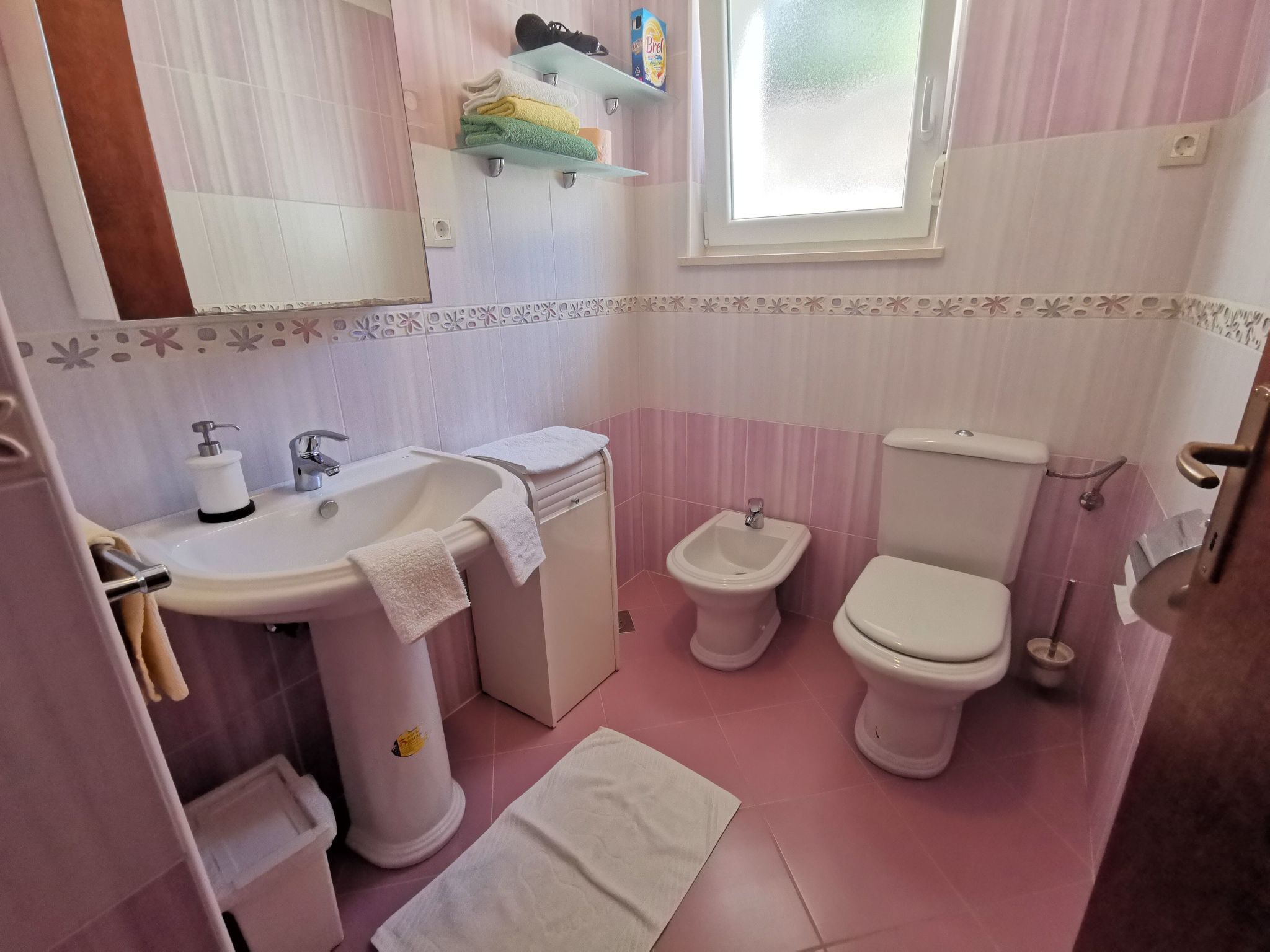 Un baño con lavamanos, bidé, inodoro y ventana.