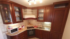 Eine kleine Küche mit Holzausstattung, einer Mikrowelle, einem Backofen und einem Spülbecken.