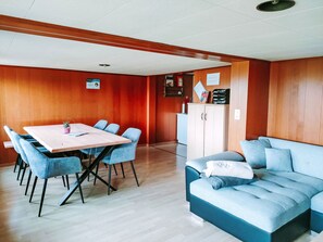 A room with a wooden paneled wall, a white cabinet, a blue sofa, and a table with chairs. - Löhli Hof by Interhome (Lienz)