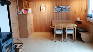 Un intérieur en bois comprenant une table à manger, des bancs, une horloge et un tableau accroché au mur.
