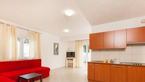 Eine moderne Wohnung mit einem roten Sofa, einem kleinen Fernseher und Küchenschränken aus Holz.