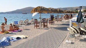 Eine Strandbucht mit Liegestühlen, Sonnenschirmen und einer Bootsanlegestelle.