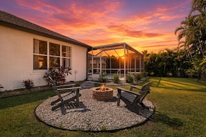 A house with a screened porch, a fire pit, and outdoor seating. - South Cape Luxury | Putt Green, HTD POOL,& Game RM (Cape Coral)