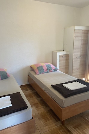 Een slaapkamer met twee eenpersoonsbedden, een garderobe en een nachtkastje.