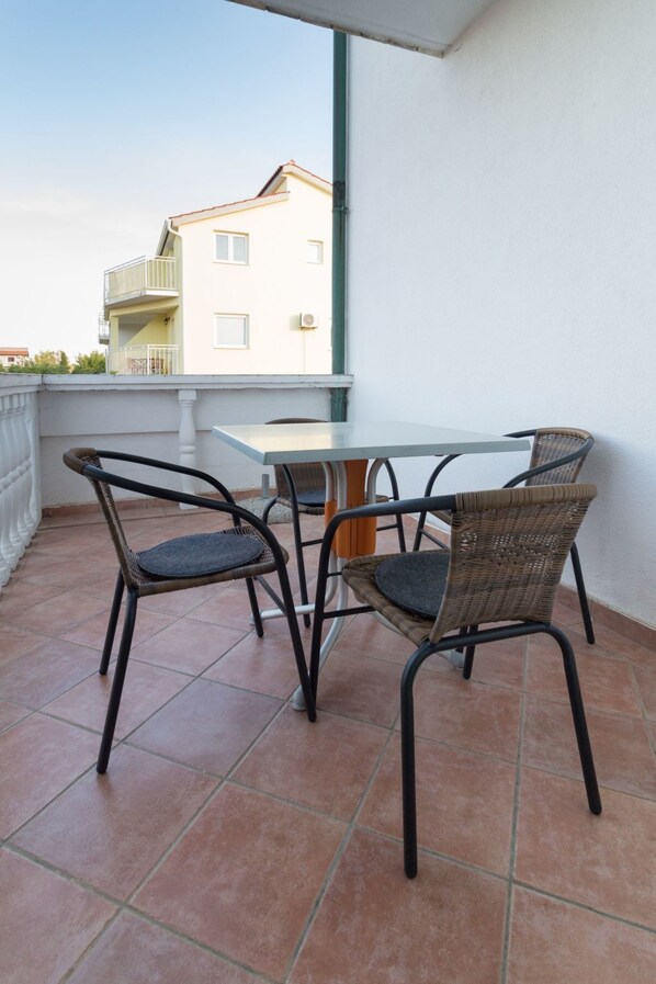 Ein Balkon mit Tisch und zwei Korbstühlen.