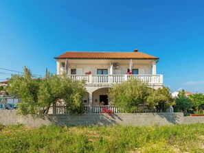 Ein zweistöckiges Gebäude mit Balkon, überdachter Veranda und einer Statue an der Fassade.