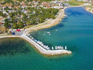 Ein Luftbild einer Küstenregion mit einer Marina, Strand und Wohngebäuden.