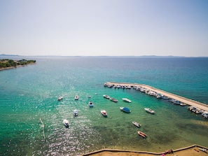 Uma marina costeira com barcos atracados ao longo de um molhe de areia.